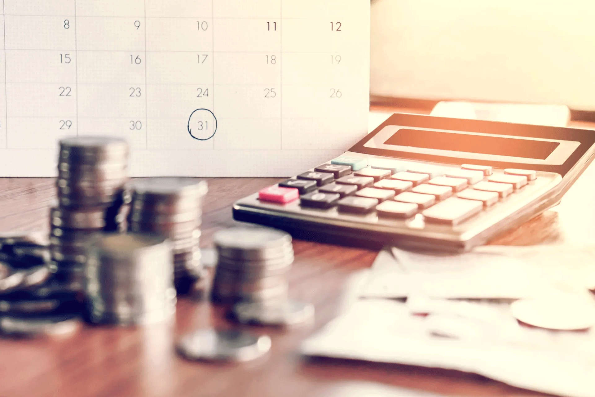 An image of a calculator, money and calendar on a desk