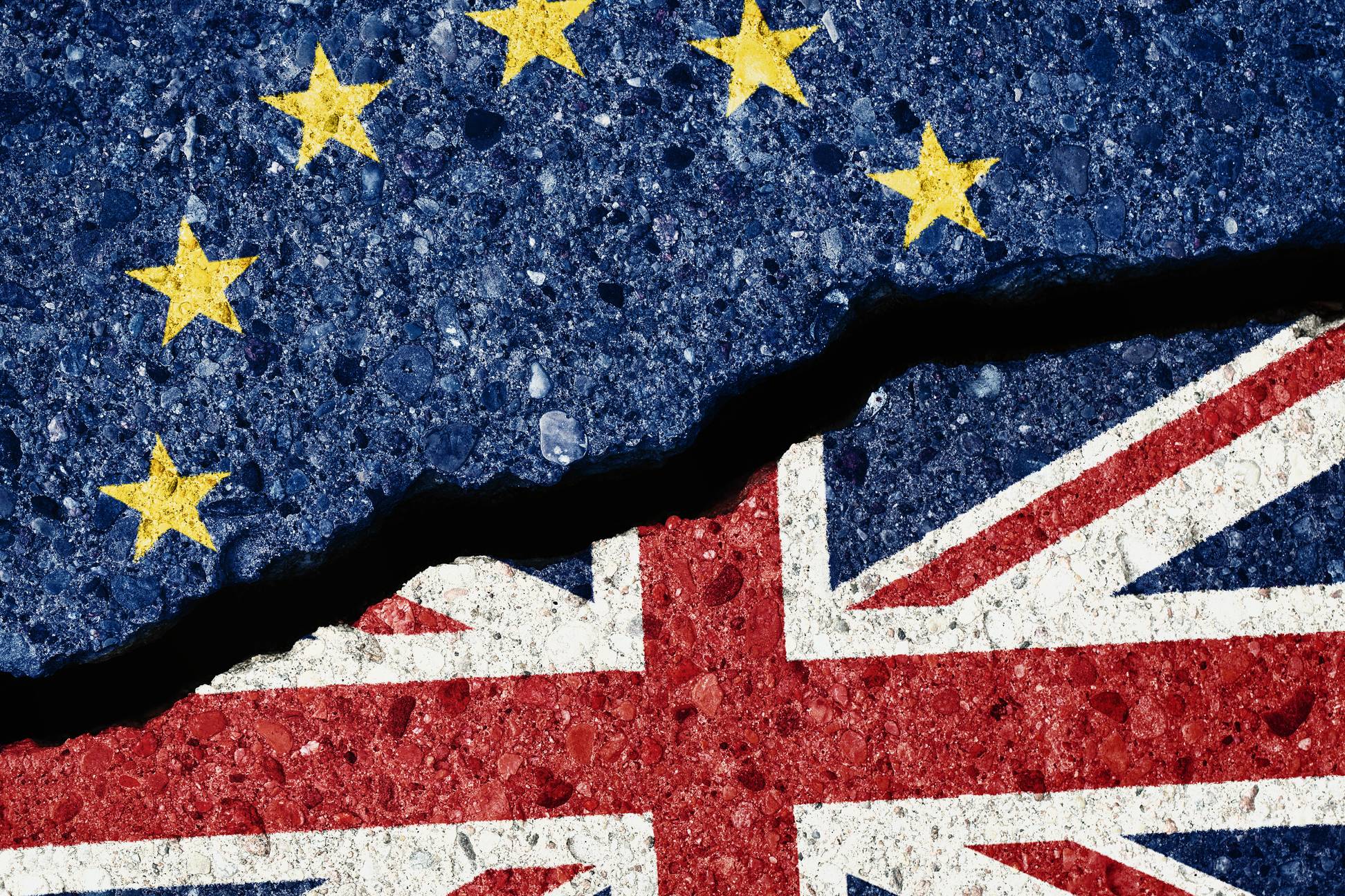 Brexit concept, crack in the asphalt dividing the UE and GB flags