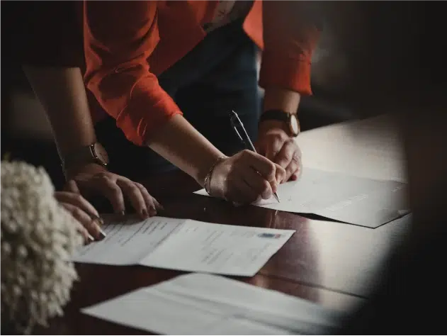 Two individuals signing paperwork related to customs compliance costs