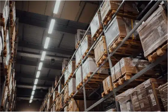 An image of the inside of a warehouse with shelves of boxes and pallets.