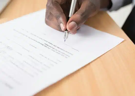 An image of a person signing a piece of paper.